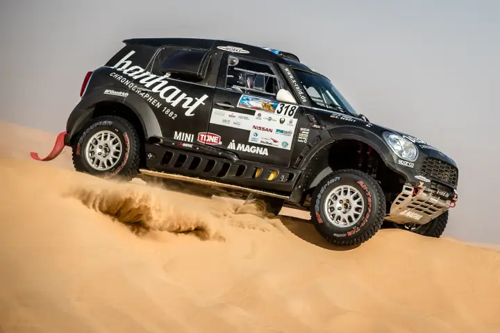 Abu Dhabi Desert Challenge 2018: Mini car on sand dune with dust cloud