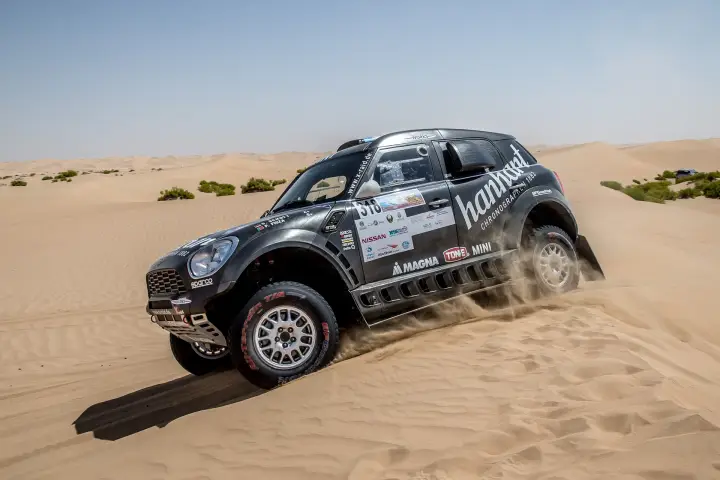 Abu Dhabi Desert Challenge 2018: black Mini rally car sliding through desert sand
