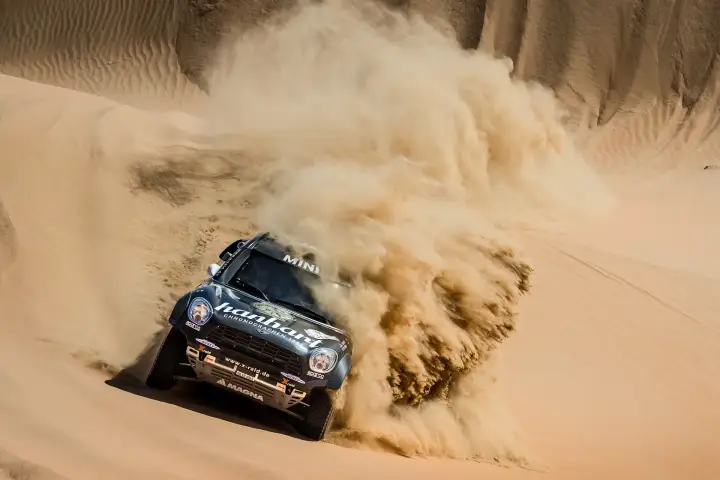 Abu Dhabi Desert Challenge 2018: Mini car cresting dune spraying huge sand rooster tail