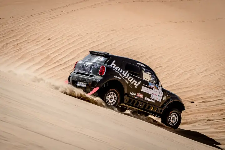 Abu Dhabi Desert Challenge 2018: Mini car descending dune kicking up sand trail