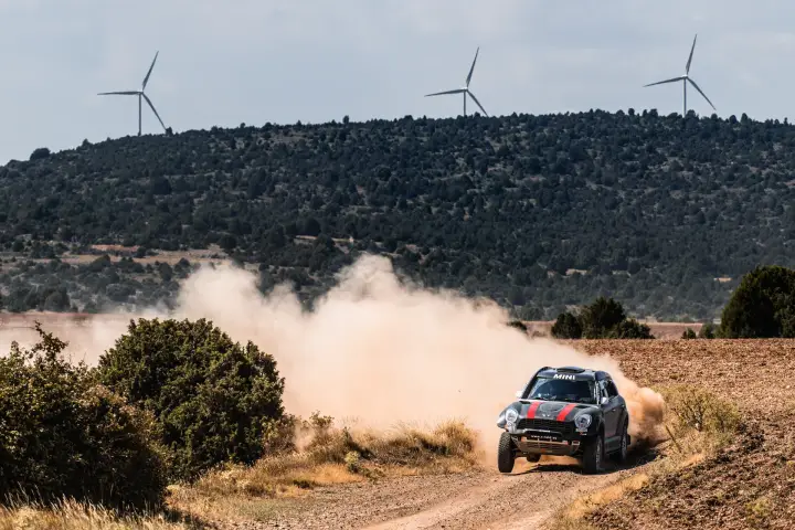 Baja Aragón 2021: dark Mini racing with wind turbines in background