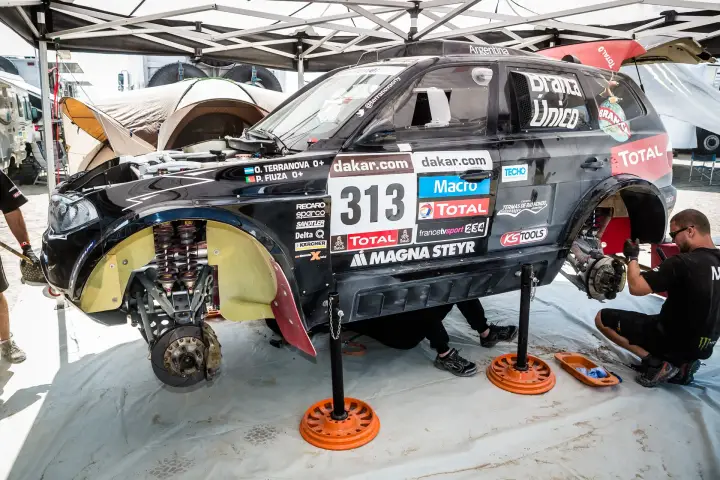 Dakar Rally 2013: mechanics servicing BMW with wheels removed bivouac