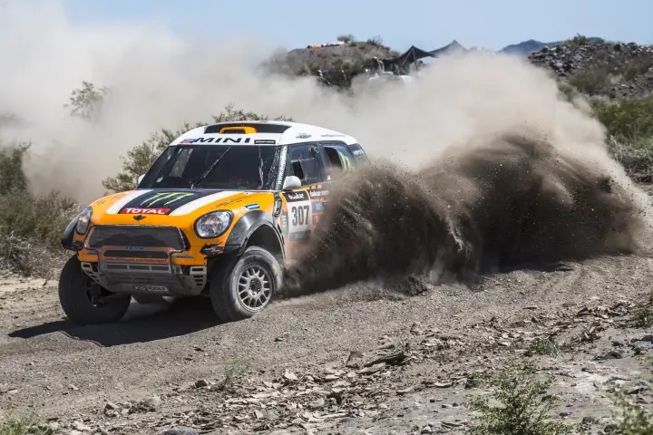 Dakar Rally 2014: Mini raising dust cloud beside rocky cliff