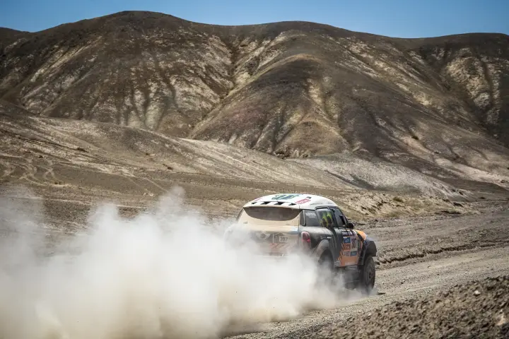 Dakar Rally 2014: Mini rear view raising dust on barren hills