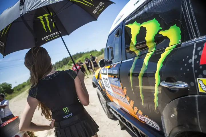 Dakar Rally 2014: Monster Energy girl holds umbrella by car