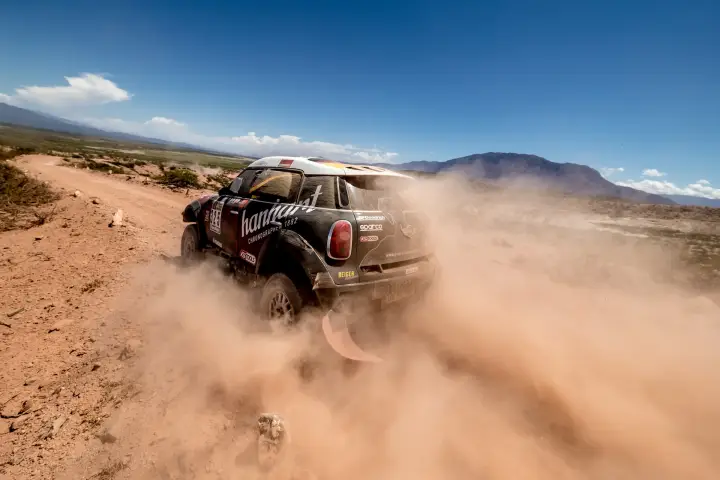 Dakar Rally 2017: Mini rear view throwing dust on barren plain