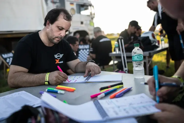 Dakar Rally 2017: navigator studying roadbook with highlighters at table