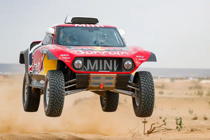 Dakar Rally 2020: red Mini buggy airborne over desert sand