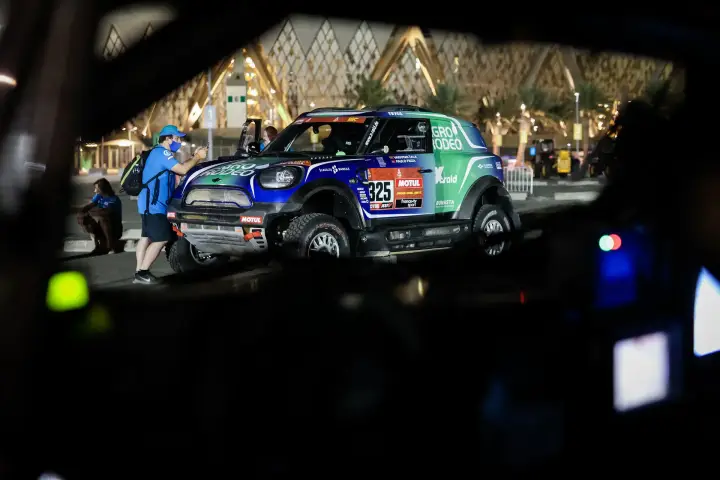 Dakar Rally 2021: race car at night near illuminated Saudi building