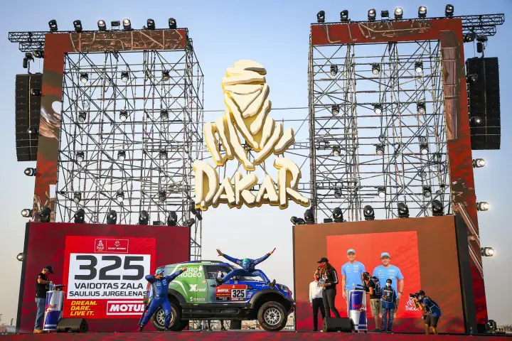 Dakar Rally 2021: car and crew on Dakar stage under golden logo