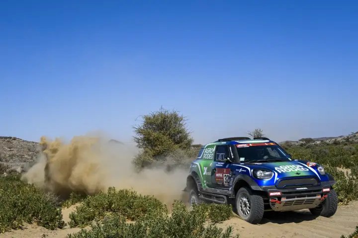 Dakar Rally 2021: blue Mini cornering through sandy desert bushes