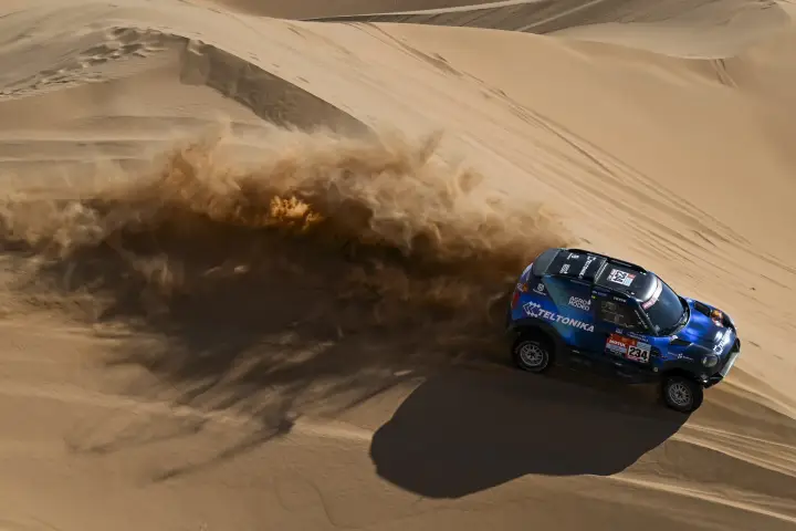 Dakar Rally 2022: rally car kicking massive sand wave dune