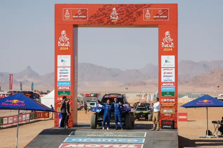 Dakar Rally 2024: two drivers posing under Dakar 2024 finish arch