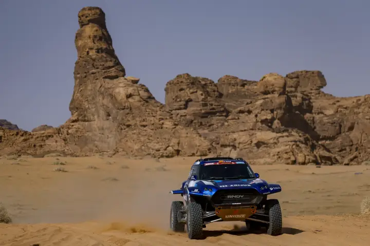 Dakar Rally 2024: rally buggy driving past towering desert rock formations