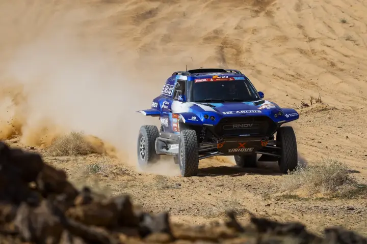 Dakar Rally 2024: blue buggy charging rocky gravel desert terrain
