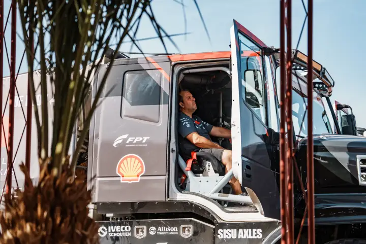 Dakar Rally 2025: driver seated in truck cab through palm leaves