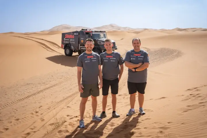 Dakar Rally 2025: three crew members posing in desert truck behind