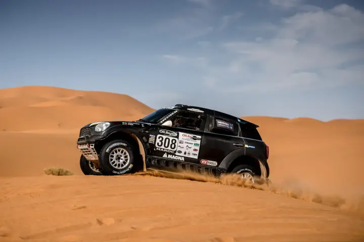Rallye du Maroc 2016: black Mini side view on wide orange Moroccan dune
