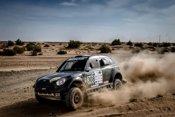 Rallye du Maroc 2016: black Mini turning on flat Moroccan dusty terrain