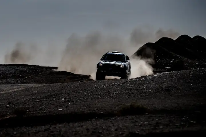 Rallye du Maroc 2016: dark silhouette Mini racing over Moroccan black terrain