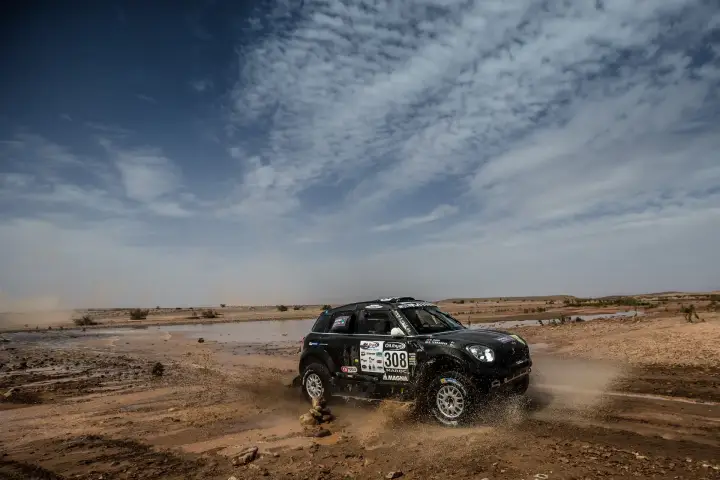 Rallye du Maroc 2016: black Mini racing across flat Moroccan desert plain