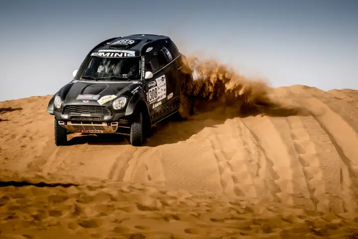 Rallye du Maroc 2016: black Mini cresting dune head-on with sand cloud