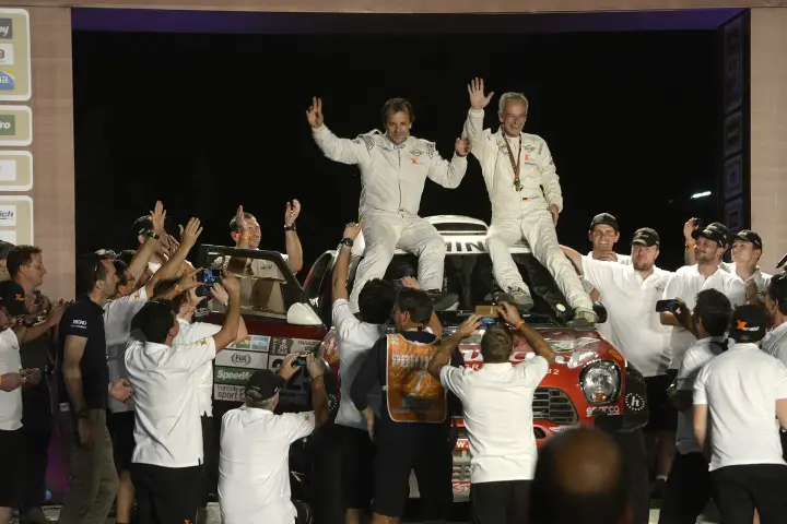 Pódio: two drivers waving on car atop celebrating crowd