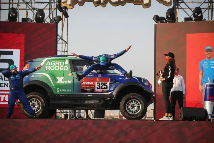 Pódio: driver jumping on car roof at Dakar 2021 podium stage