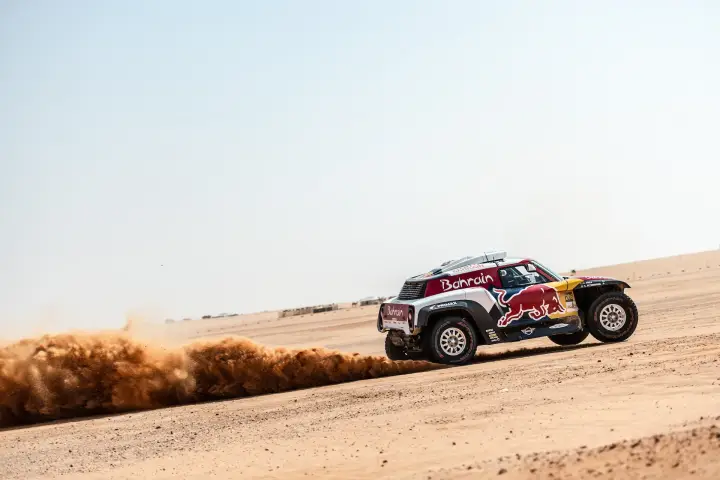 Riyadh Rally 2019: red Mini drifting on flat Saudi desert landscape